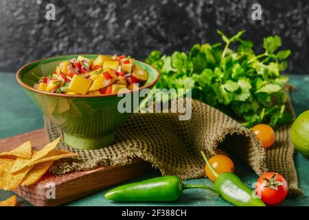 Bol avec salsa à la mangue fraîche et nachos sur fond de couleur Banque D'Images