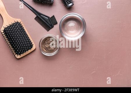 Bol avec henné, fournitures de coiffeur et verre d'eau sur fond de couleur Banque D'Images