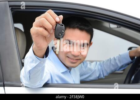Homme asiatique souriant en tant que conducteur montrant la clé de la voiture (axé sur les clés) Banque D'Images