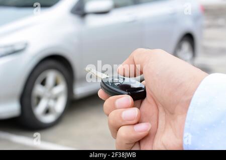 Un homme sur le point d'appuyer sur le bouton de la télécommande clé de voiture Banque D'Images