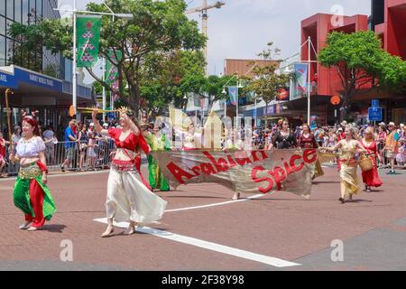 Danseuses du ventre avec des tenues colorées et une bannière « Arabian Spice » se promenant dans la rue lors d'un défilé de Noël à Tauranga, en Nouvelle-Zélande Banque D'Images