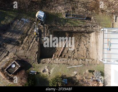 Drones vue aérienne d'un chantier de construction d'une piscine, petite pelle jaune creuse trou pour la piscine et est presque terminée dans un joli jardin en autriche Banque D'Images