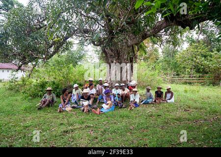 Cérémonie de Famadihana, ou le retournement des os, une tradition malgache de célébrer leurs ancêtres morts, des gens assis sous un arbre, Madagascar Banque D'Images
