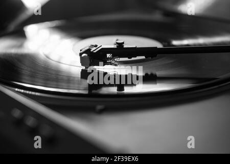 Vue rapprochée d'un enregistrement en vinyle entre l'avant-bras et le plateau tournant. Tendances du divertissement et de la musique, image en noir et blanc Banque D'Images