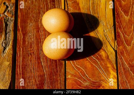 Deux œufs de poulet sur l'ancienne table en teck, vue du dessus dans peu profonde foyer Banque D'Images