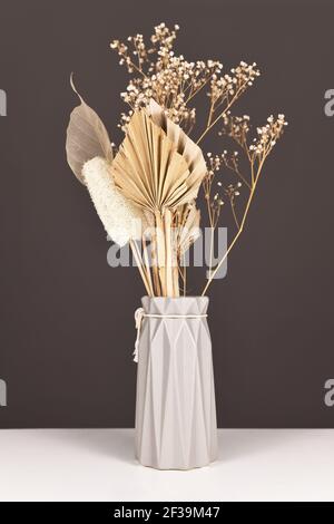 Bouquet naturel avec vase gris avec fleurs séchées et feuilles comme feuille de palmier, feuille de squelette, luffa et fleurs communes de Gypsophila