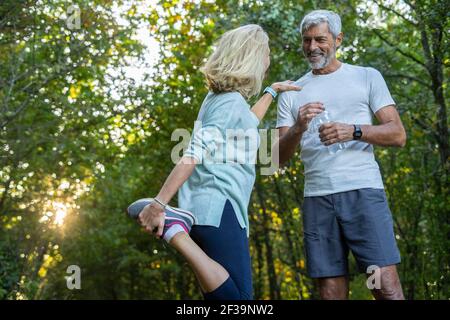 Vue à angle bas d'un couple mûr souriant parlant en forêt Banque D'Images
