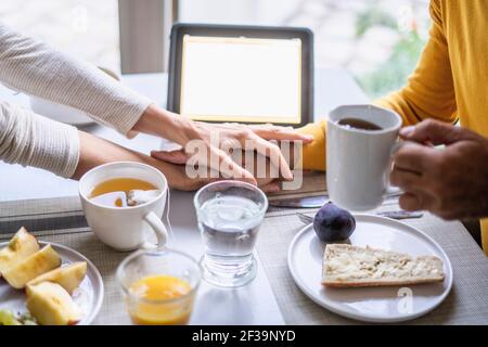 Couple d'âge mûr tenant les mains tout en prenant le petit déjeuner à table Banque D'Images