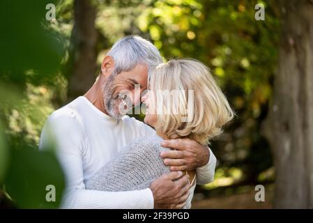 Un couple mûr souriant s'embrasse l'un l'autre dans l'arrière-cour Banque D'Images