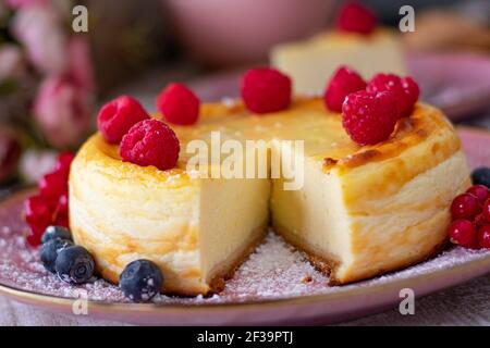 Gros plan d'un gâteau au fromage accompagné de framboises une assiette rose pâle Banque D'Images