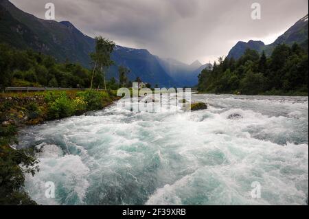 Vallée d'Oldedalen, Norvège - la pluie d'été descend au-dessus des sommets montagneux, la rivière Oldeelva en torrent plein avec de l'eau de fonte glaciaire. Banque D'Images