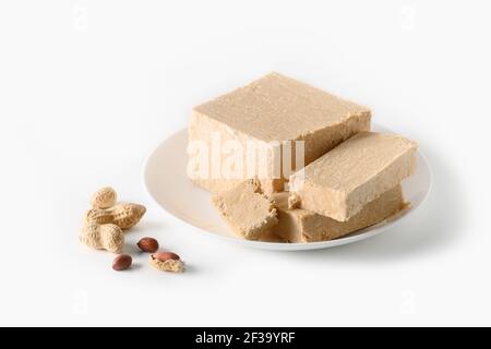 Dessert sucré de l'est de la halva d'arachide dans une assiette isolée sur fond blanc. Gros plan. Banque D'Images