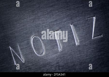 Gros plan d'une plaque métallique biseautée grise avec le mot NOTE estampillé en diagonale. Banque D'Images