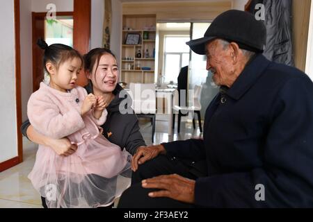 (210316) -- TAIYUAN, 16 mars 2021 (Xinhua) -- Liu Qingji (R) discute avec sa petite-fille (C) dans un complexe résidentiel pour les villageois déplacés dans la ville de Yukou, dans le comté de Fangshan, dans la province de Shanxi, au nord de la Chine, le 10 mars 2021. Shijiamao est un petit village situé dans des zones montagneuses accidentées avec peu de précipitations. Comme d'autres villageois ici, Liu Qingji, un agriculteur de 85 ans, avait l'habitude de faire de l'agriculture à la merci des éléments. Ayant résidé de nombreuses années dans une sombre « yaodong », une maison construite dans la terre endurcie commune à travers le plateau de Loess, dans le nord de la Chine, Liu espérait améliorer la vie Banque D'Images