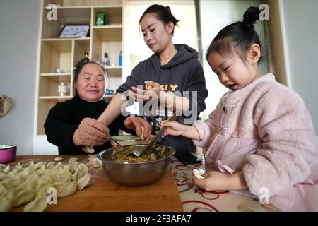 (210316) -- TAIYUAN, 16 mars 2021 (Xinhua) -- Gao Jilian (1er, L) et Liu Xiaomei (C), belle-fille et petite-fille de Liu Qingji, font des boulettes avec la grande petite-fille de Liu Qingji dans un complexe résidentiel pour les villageois déplacés dans la ville de Fangshan, province de Shanxi, dans le nord de la Chine, le 10 mars 2021. Shijiamao est un petit village situé dans des zones montagneuses accidentées avec peu de précipitations. Comme d'autres villageois ici, Liu Qingji, un agriculteur de 85 ans, avait l'habitude de faire de l'agriculture à la merci des éléments. Après avoir redoré de nombreuses années dans un sombre 'yaodong', une maison construite dans Banque D'Images