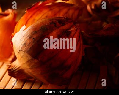 L'utilisation de peaux d'oignons en médecine et pour colorer les oeufs de Pâques. Peau d'oignon et oignon sur fond en bois. Banque D'Images