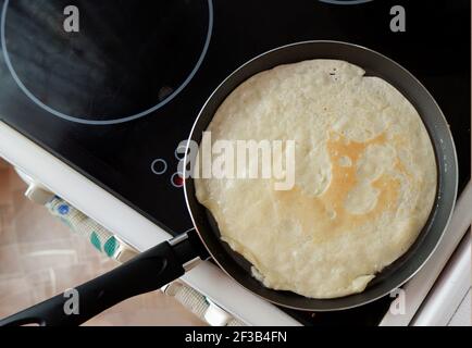 une crêpe est frite dans une poêle sur un cuisinière électrique Banque D'Images