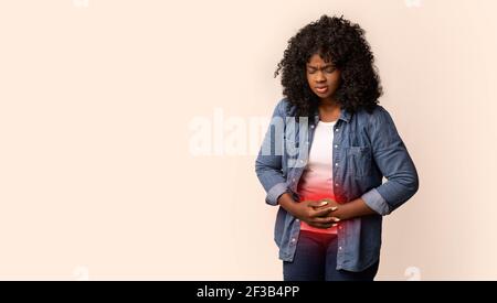 Contrarié jeune femme afro-américaine souffrant de douleurs abdominales Banque D'Images