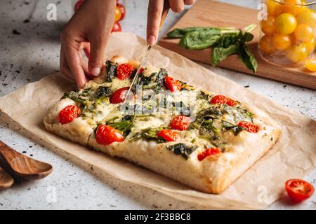 Trancher à la main la focaccia du pain italien avec les épinards Banque D'Images