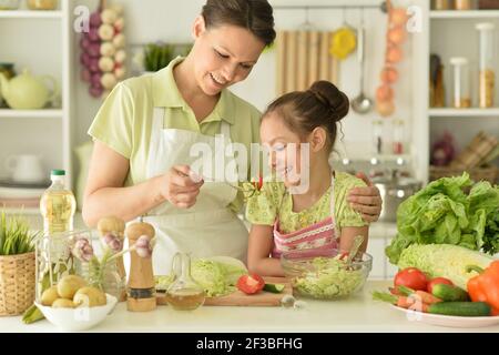 Jolie petite fille avec sa mère à cuisiner ensemble table de cuisine Banque D'Images