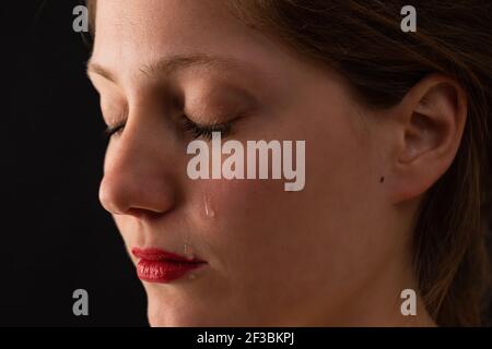 Triste femme pleurant avec des yeux fermés dans un environnement sombre Banque D'Images