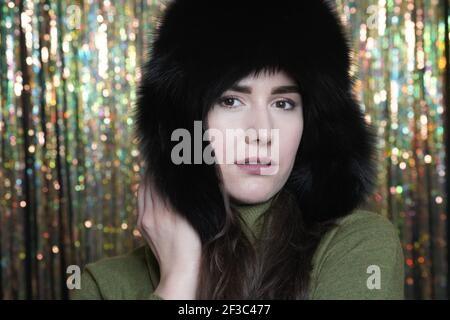 Portrait d'une femme de style décontracté en hiver chapeau en fourrure gros plan, visage et mains sur fond étincelant Banque D'Images