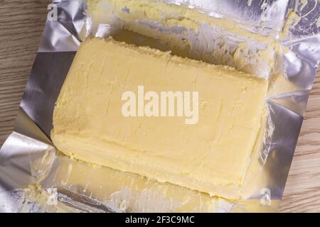 Ouvrir paquet de beurre salé sur fond de bois Banque D'Images