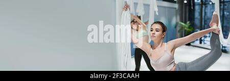 Jeune femme se réchauffant avec des lanières de yoga à la mouche dans le centre sportif, bannière Banque D'Images