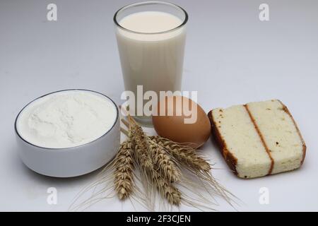 gâteau et blé mûr et oeuf et lait et atta sur fond blanc Banque D'Images