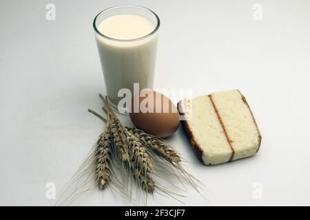 gâteau et blé mûr et oeuf et lait et atta sur fond blanc Banque D'Images