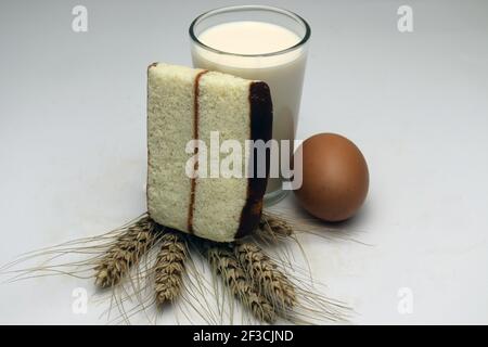 gâteau et blé mûr et oeuf et lait et atta sur fond blanc Banque D'Images