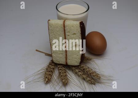 gâteau et blé mûr et oeuf et lait et atta sur fond blanc Banque D'Images