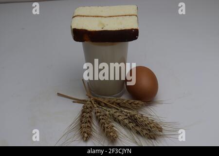 gâteau et blé mûr et oeuf et lait et atta sur fond blanc Banque D'Images