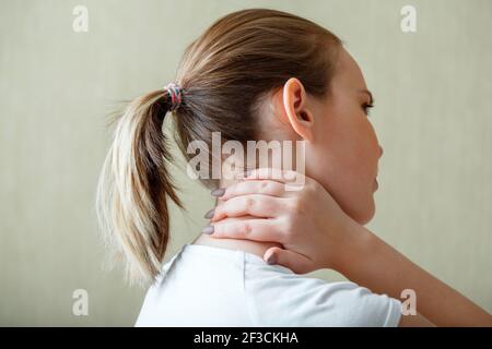 Douleur de cou d'épaule, vertèbres cervicales. La femme tient le cou avec douleur spasme du muscle cervical à la main. Maladie du système musculo-squelettique chez la jeune femme. Il Banque D'Images