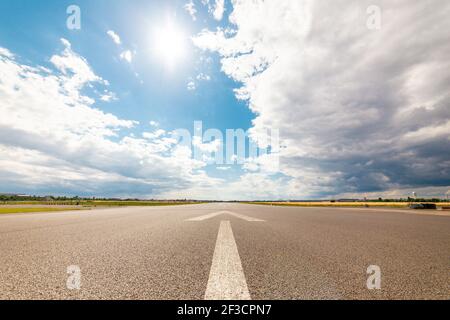 Une photo grand angle d'une route sous la lumière du soleil et un ciel bleu nuageux Banque D'Images