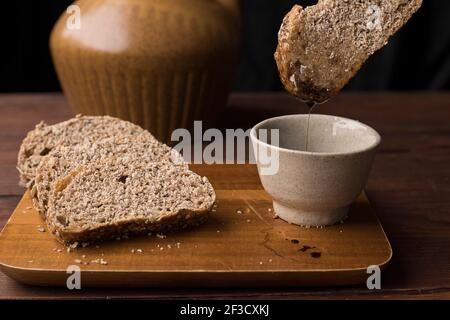 Une photo de studio de tremper une tranche de pain de blé dans de l'huile et du vinaigre balsimique. Banque D'Images