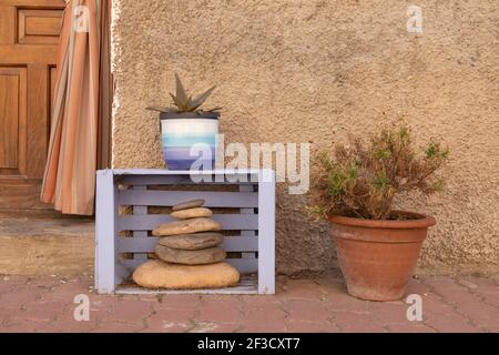 Un charmant coin de maison drôle dans la petite ville d'Ambel, composé d'une ancienne boîte en bois, peint violet, et quelques pierres de rivière à côté de quelques plantes en pot Banque D'Images