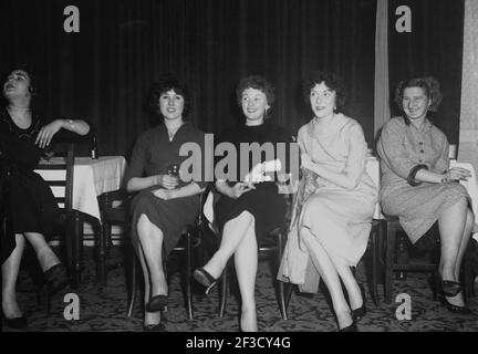 1957, historique, soirée et quatre jeunes femmes dans la mode féminine de l'époque assis sur des chaises dans une salle de réception de l'hôtel Victoria à une fête de bureau, peut-être par le regard amusant sur leurs visages, regardant d'autres danser, Leeds, Angleterre, Royaume-Uni. Banque D'Images