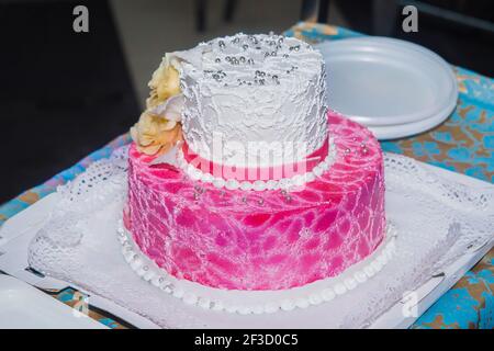 Gâteau de mariage blanc et rose à deux niveaux avec décoration en perles sur un plateau Banque D'Images