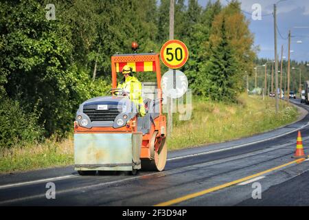 Le conducteur de rouleau sur route travaille sur route. L'autoroute d'asphaltage en Finlande en été. Banque D'Images