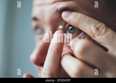 Jeune homme mettant la lentille de contact sur les yeux. Thèmes vue et routine quotidienne. Banque D'Images