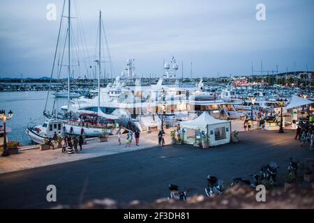 Port d'Alghero au crépuscule en Sardaigne. La marina a plusieurs bateaux nautiques amarrés pour la soirée. De nombreux yachts de luxe, et des bateaux. Banque D'Images