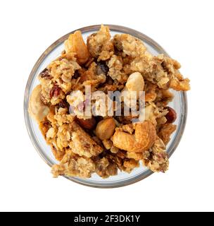 Vue de dessus d'un petit bol en verre rempli de céréales complètes granola avec fruits et noix illuminés de lumière naturelle. Banque D'Images