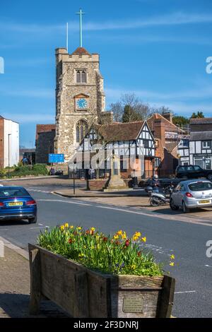 Pinner Village High Street avec église médiévale au sommet d'une colline St Jean-Baptiste, boîte de fleurs de jonquilles, mémorial de guerre et bâtiments historiques à colombages. Banque D'Images