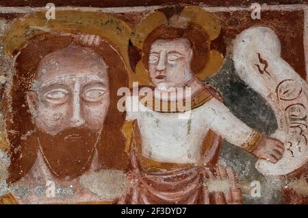 L’enfant du Christ tient aux cheveux de St Christopher tout en étant assis sur son épaule gauche. Détail d'une fresque médiévale endommagée dans une église romane, la Chiesa di Santa Maria del Tiglio, construite en 1100s à côté du lac de Côme à Gravedona, Lombardie, Italie. St Christopher, le Saint patron des voyageurs, porte un lourd double fardeau alors qu’il forge une rivière dangereusement gonflée : le poids de l’enfant Jésus combiné au poids des péchés du monde. Gravedona était autrefois un carrefour important et un arrêt pour les marchands traversant les Alpes. Banque D'Images