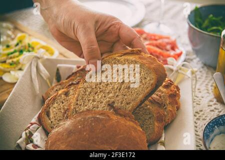 Un pain coupé en tranches dans une main. Un petit-déjeuner continental sain contenant du pain maison. Pain à base d'épeautre et de farine de seigle avec l'addition Banque D'Images