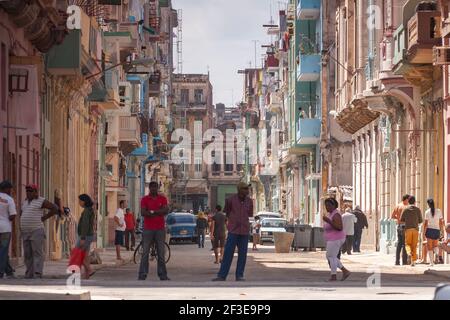 La Havane, Cuba - 23 mars 2010 : plusieurs personnes marchent le long d'une rue typique avec des bâtiments aux couleurs vives, mais vieux et en mauvais état, dans le centre Banque D'Images