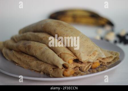 Crêpes ou crêpes plantain faites maison avec mélange de raisins de coco plantain au milieu. Prise de vue sur fond blanc. Banque D'Images