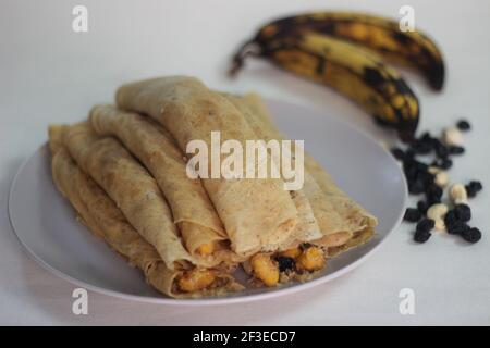 Crêpes ou crêpes plantain faites maison avec mélange de raisins de coco plantain au milieu. Prise de vue sur fond blanc. Banque D'Images