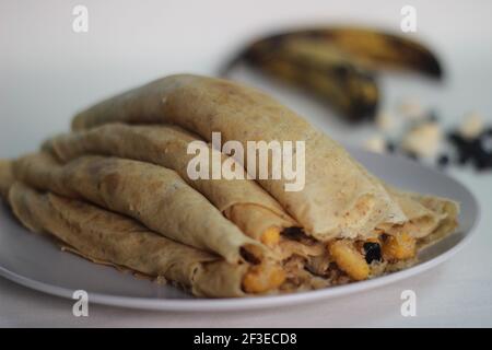 Crêpes ou crêpes plantain faites maison avec mélange de raisins de coco plantain au milieu. Prise de vue sur fond blanc. Banque D'Images